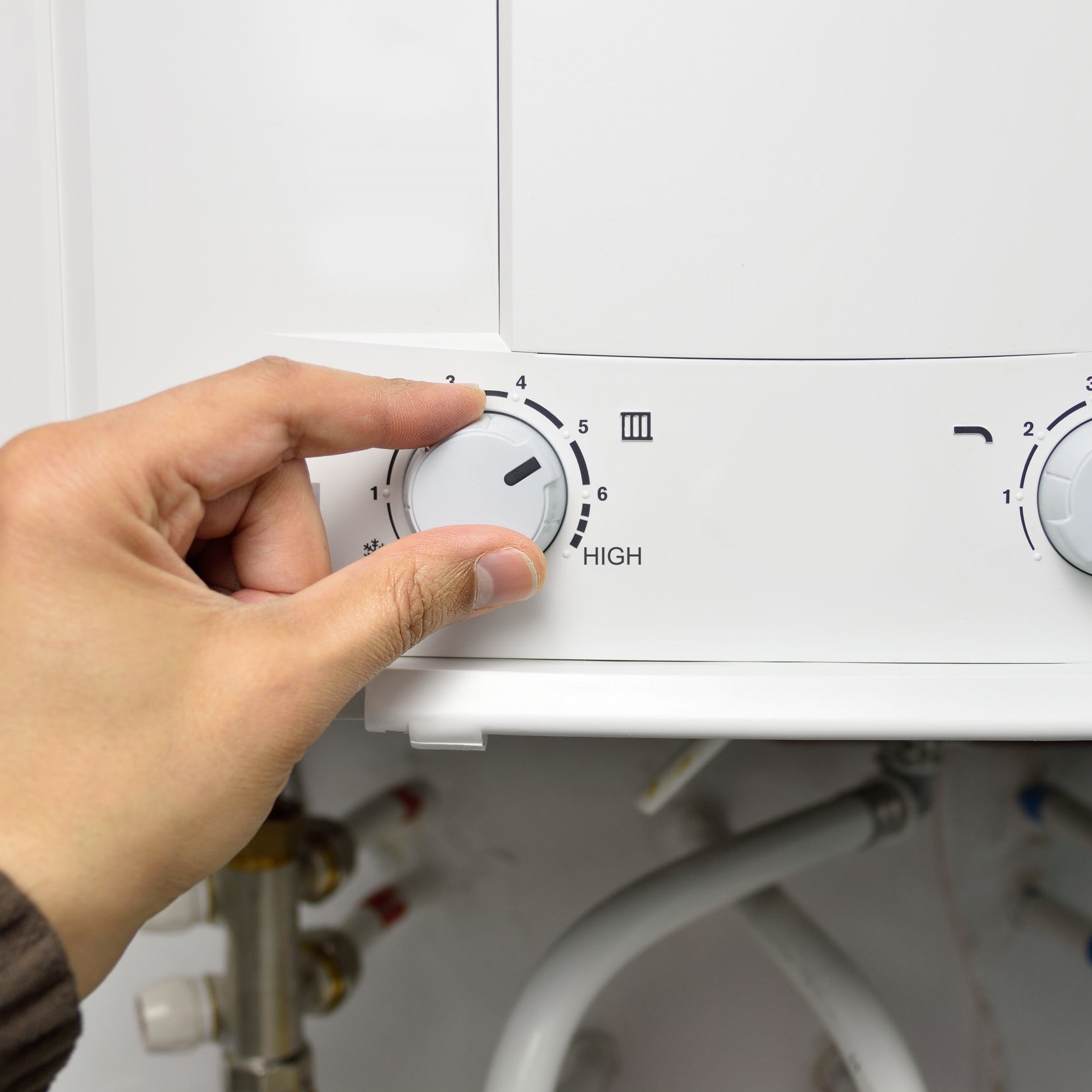 A hand on the knob of a tankless water heater.